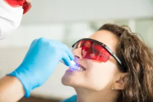 closeup young woman having her teeth whitened with ultraviolet light dental clinic