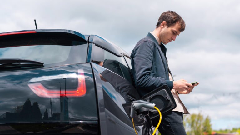 man charging his electric car charge station using smartphone 1